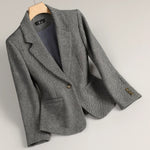 Gray tweed blazer with notch lapels, single-breasted front, gold-tone buttons at cuffs