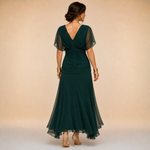 Back view of dark green maxi dress with V-back and sheer flutter sleeves, flowing hem
