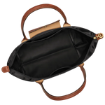 Black tote bag open inside shows tan lining, zipper top, gold pull, leather handles
