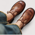 Brown Mary Jane flats with buckle strap and brogue stitching on leather-like uppers