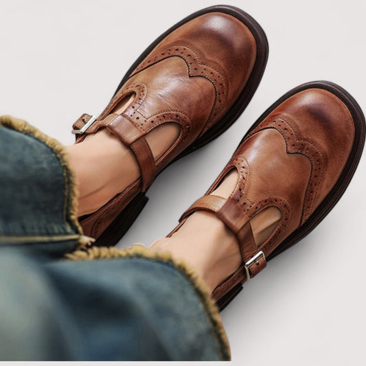 Brown Mary Jane flats with buckle strap and brogue stitching on leather-like uppers