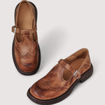 Pair of brown Mary Jane flats with buckle strap, stitched detailing, and low block heel