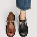 Brown and black Mary Jane flats with buckle strap, stitched panels, and thick sole