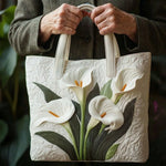 White quilted tote bag with lily floral applique, shown with hands gripping handles